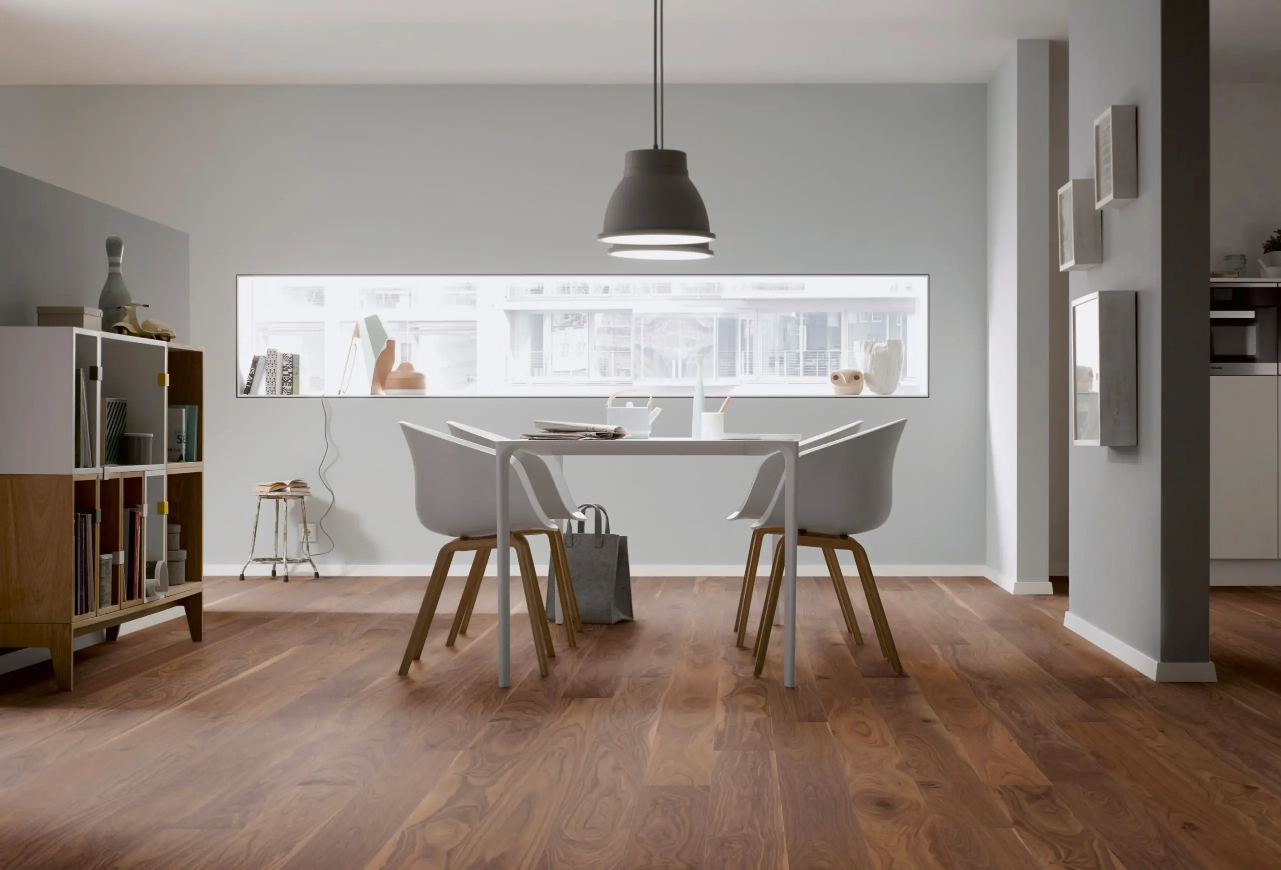 Parkettboden in Nussbaumoptik im modernen Essbereich mit Tisch und weißen Stühlen.