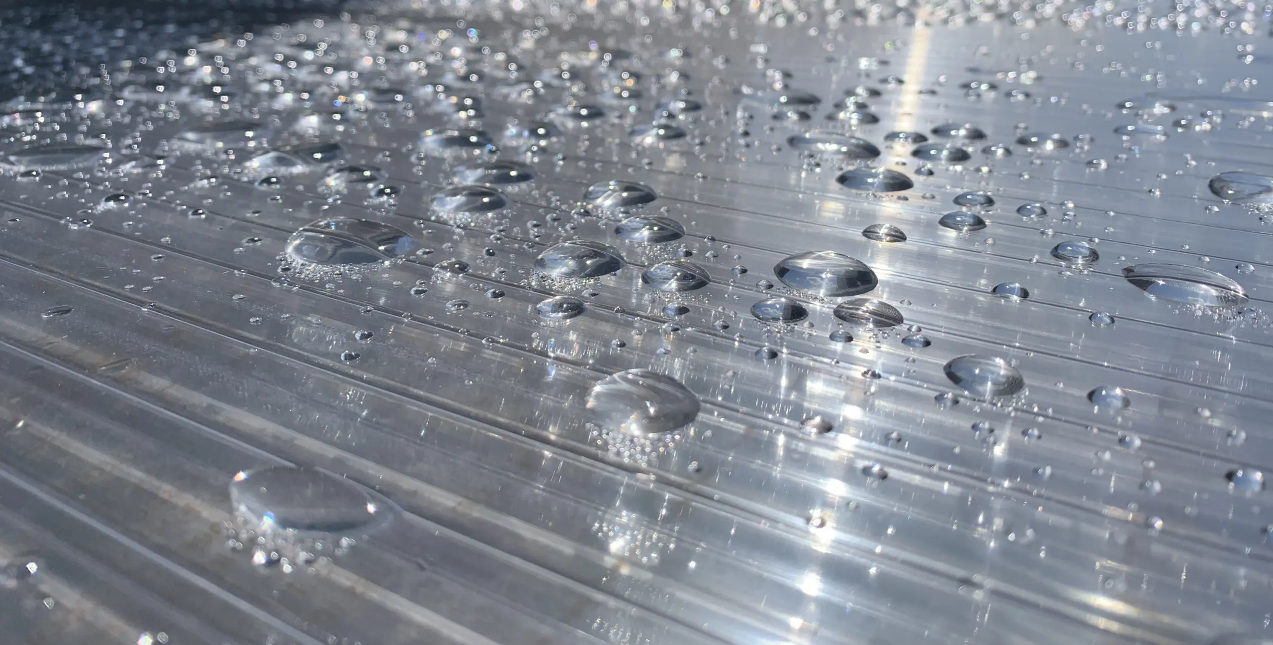 Stegplatte mit Regentropfen – Nahaufnahme einer Überdachung bei Regenwetter.