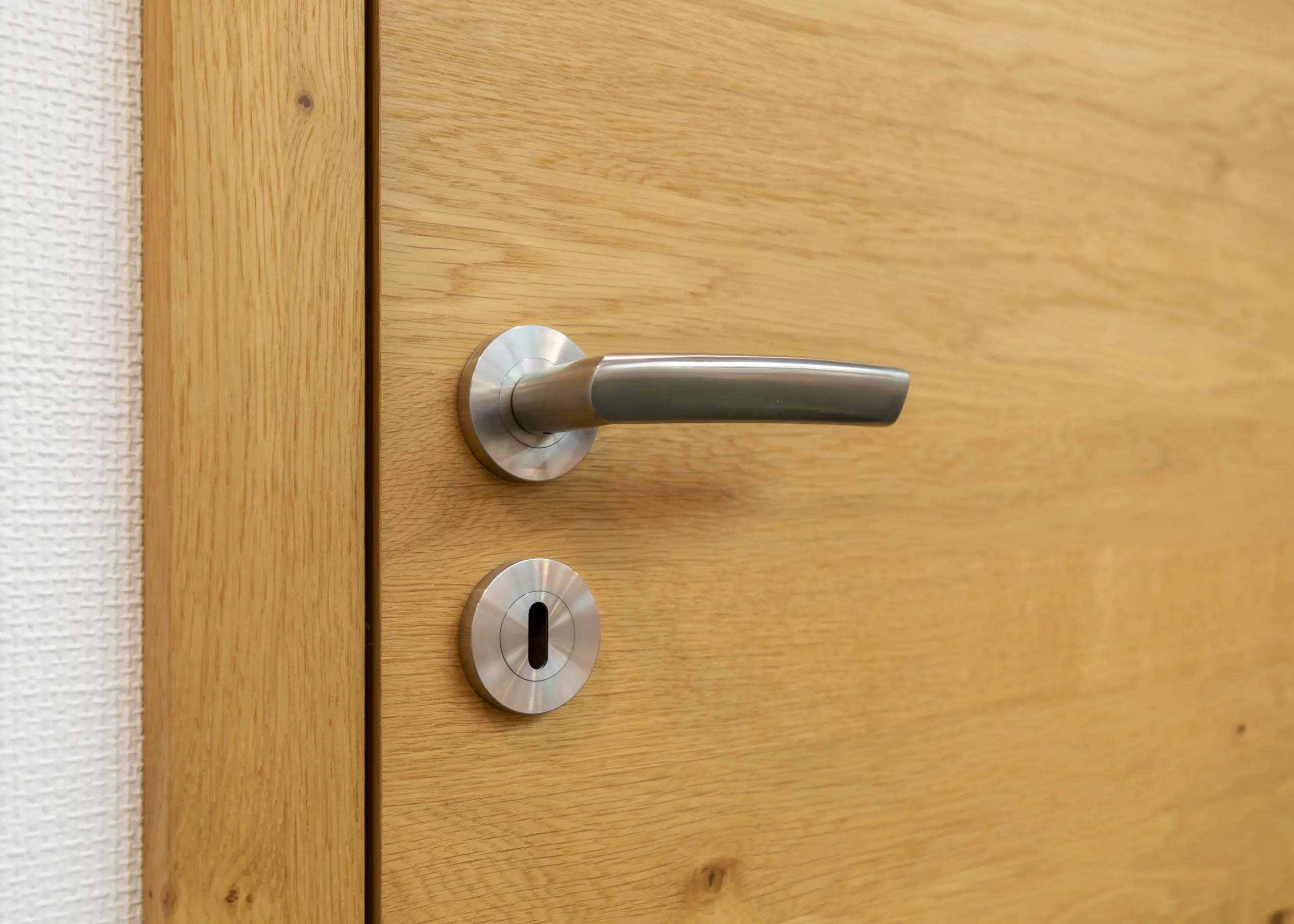 Stumpfeinschlagende Echtholztür ohne sichtbare Falz mit moderner Edelstahl-Drückergarnitur 